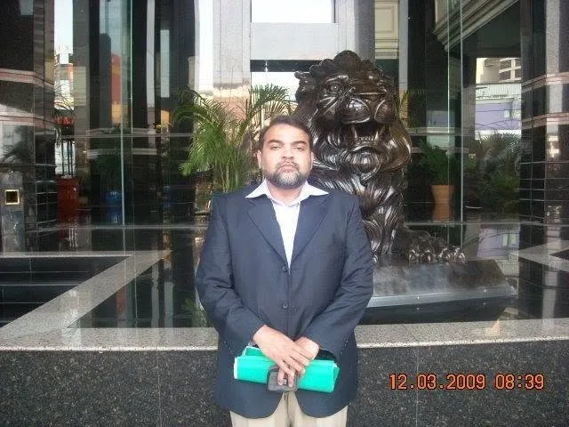 Prix Pharmaceutica Director standing beside a lion statue at a building entrance during an international business visit